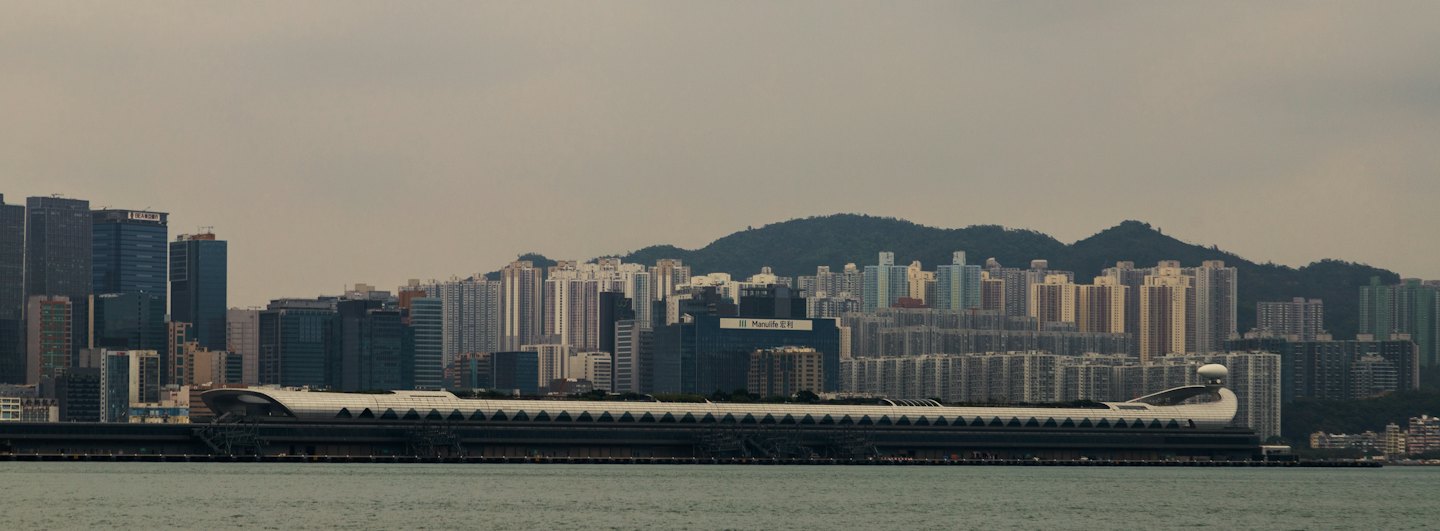 Modern buildings line the coast with hills in the distance.